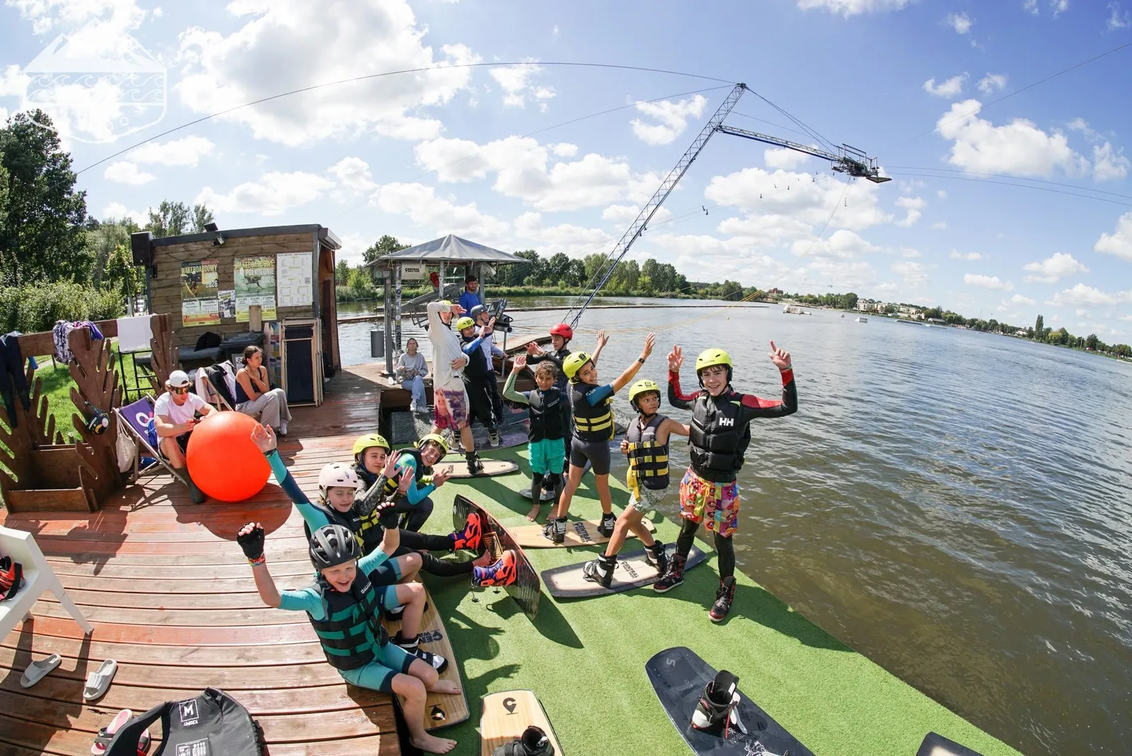Dziecko płynące na wakeboardzie podczas obozów VHSBOARD, obserwowane przez instruktora i grupę dzieci