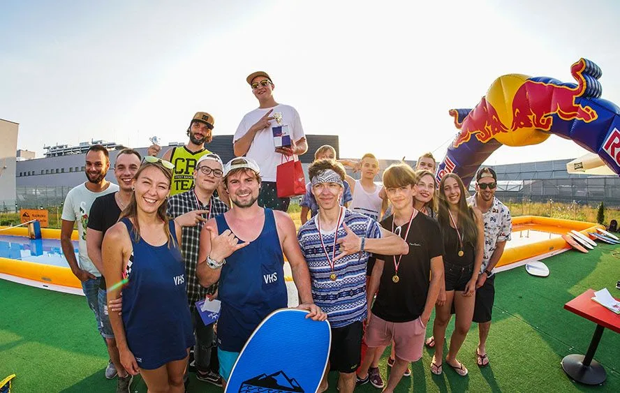 Dziecko uczące się skimboardingu pod opieką instruktora na mobilnym torze